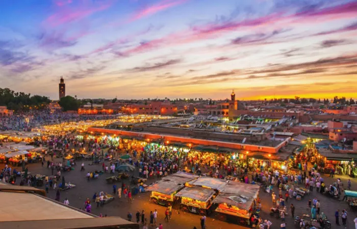Place Jemaa el-Fna à Marrakech au coucher du soleil avec foule et étals du marché nocturne
