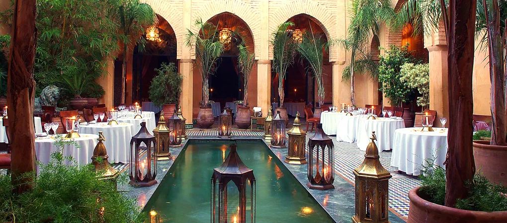 Restaurant de riad à Marrakech avec bassin, lanternes en laiton et arcades traditionnelles