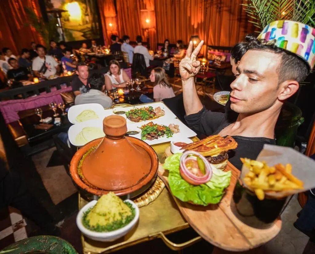 Plateau de spécialités marocaines, tajine, burger et frites dans un restaurant animé de Marrakech