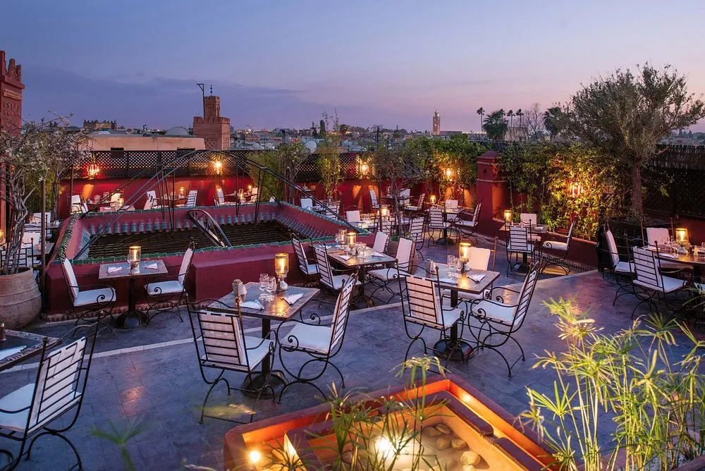 Terrasse rooftop d'un restaurant à Marrakech au crépuscule avec vue sur la médina et la Koutoubia