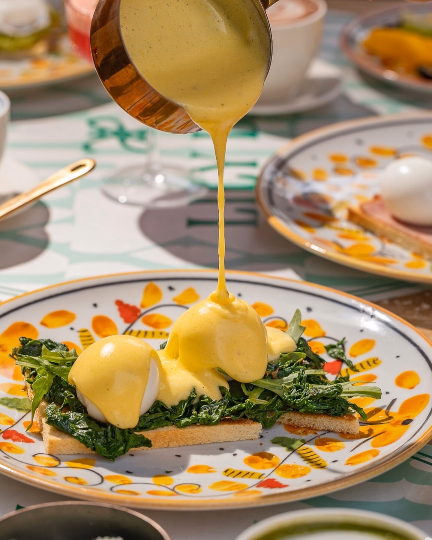Hollandaise poured over Eggs Benedict on spinach toast, a great breakfast in Marrakech